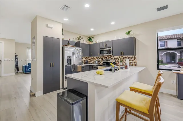 a kitchen with stainless steel appliances kitchen island granite countertop a refrigerator and a stove