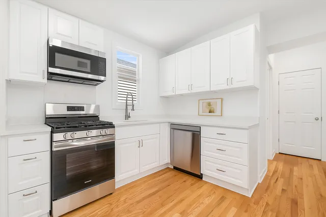 a kitchen with stainless steel appliances white cabinets and a stove top oven