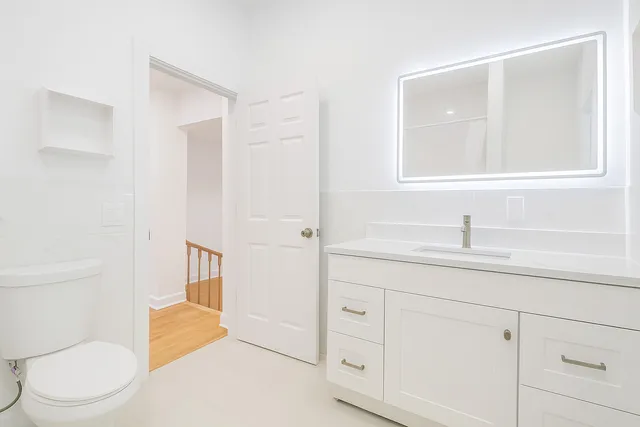 a bathroom with a toilet a sink a mirror and vanity