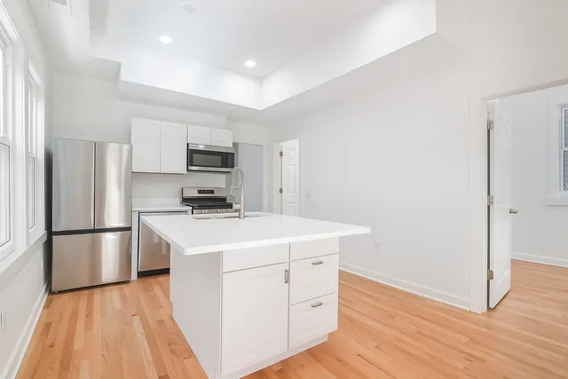 a kitchen with a refrigerator a stove top oven and wooden floor