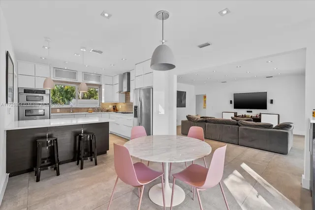 a kitchen with stainless steel appliances granite countertop a dining table chairs stove refrigerator and cabinets