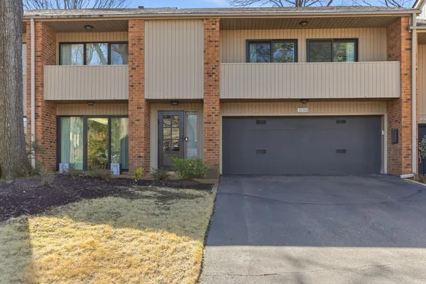 a view of a house with a small yard and a large parking space