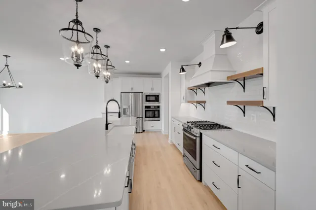 a kitchen with stainless steel appliances granite countertop a sink dishwasher a stove and a refrigerator with wooden floor