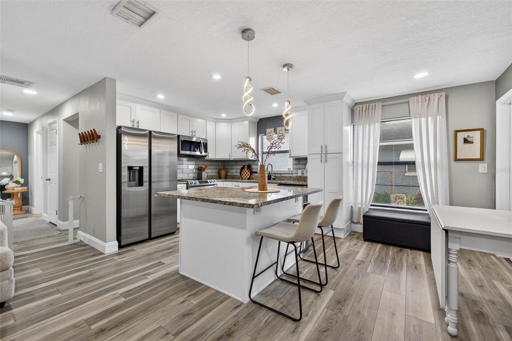 6501 Livingston Avenue North St. Petersburg, FL 33702 - Photo 5 of 31 a kitchen with stainless steel appliances a refrigerator a stove a sink dishwasher with a dining table and chairs