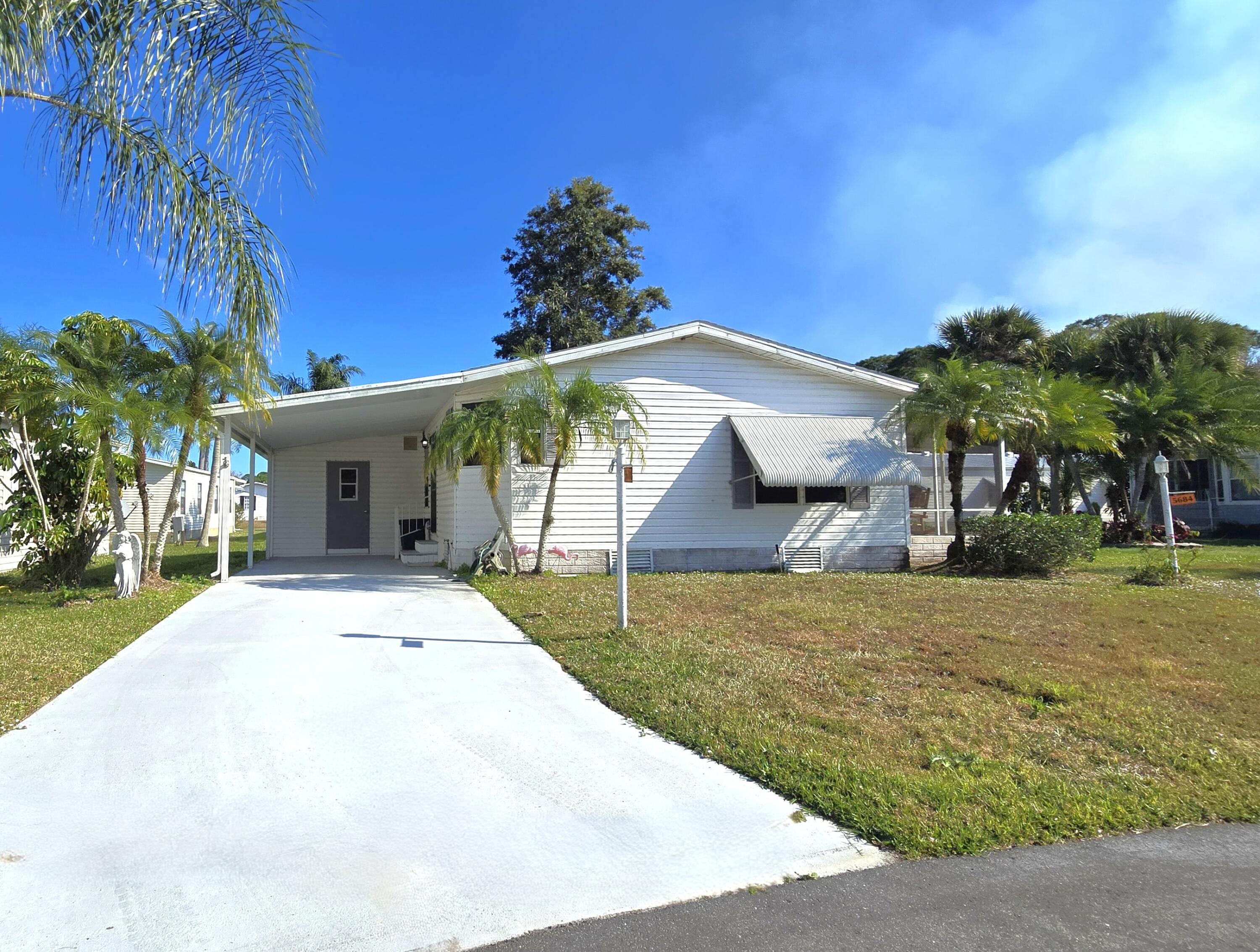 5680 Hemingway Court, Unit 15 Fort Pierce, FL 34982 - Photo 2 of 18 a front view of a house with a yard and potted plants