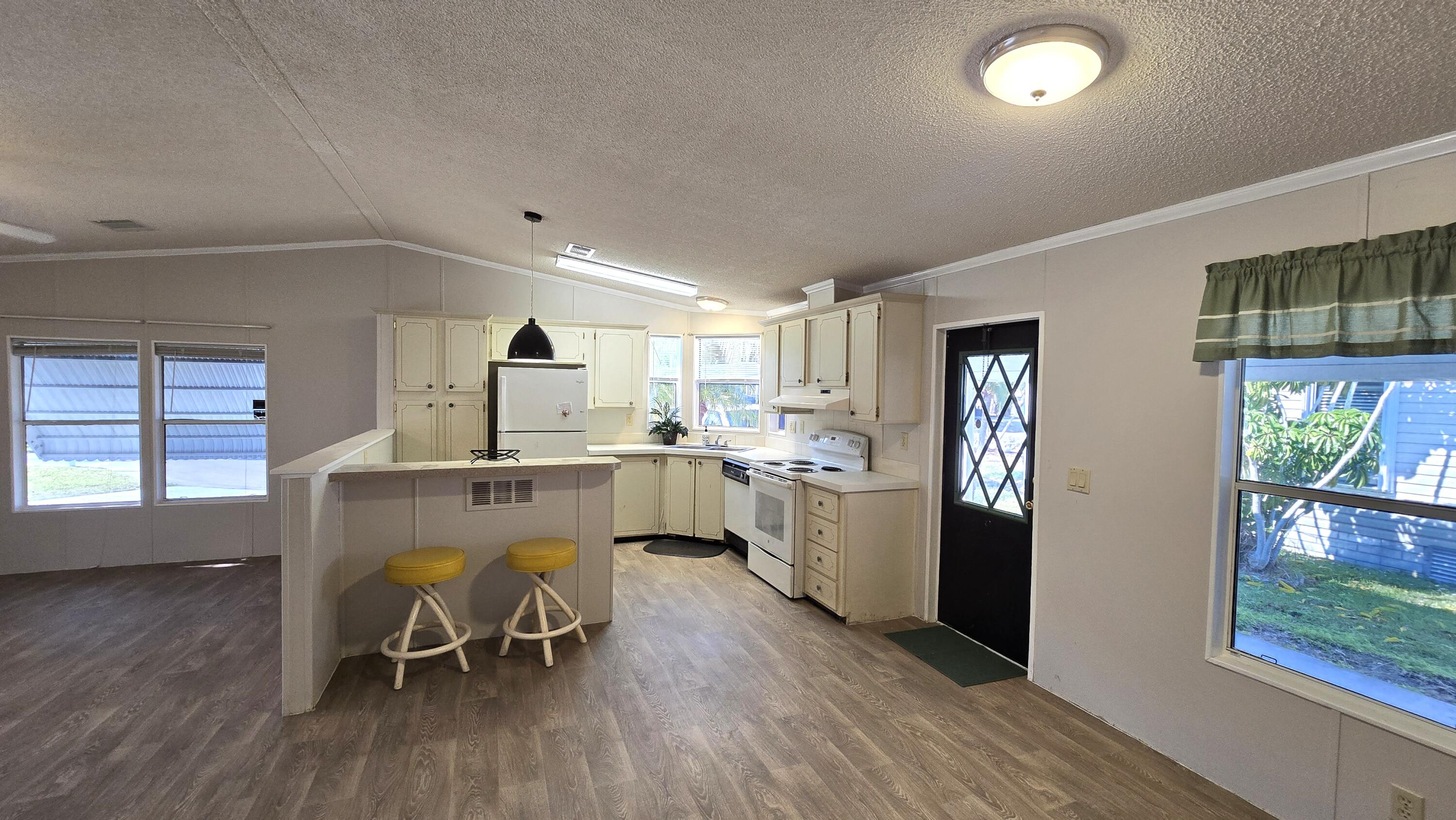 5680 Hemingway Court, Unit 15 Fort Pierce, FL 34982 - Photo 7 of 18 a kitchen with a dining table chairs refrigerator and cabinets