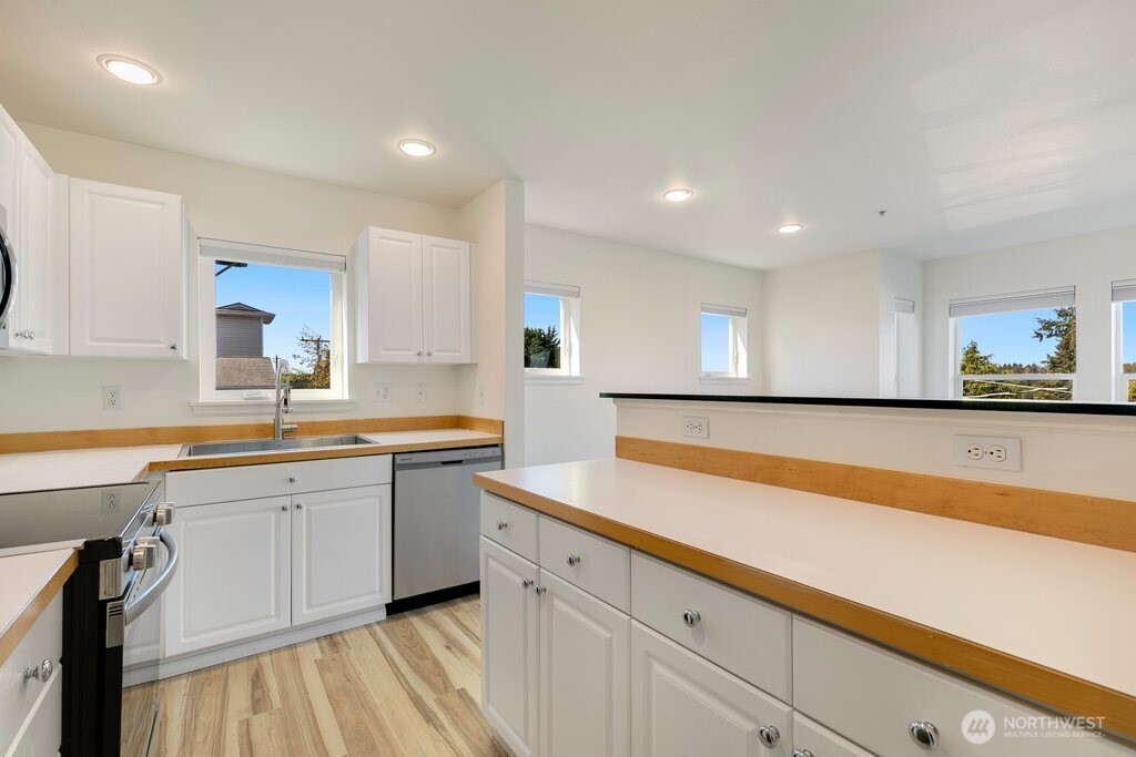 2101 North 55th Street, Unit 201 Seattle, WA 98103 - Photo 11 of 24 a kitchen with granite countertop white cabinets and white appliances