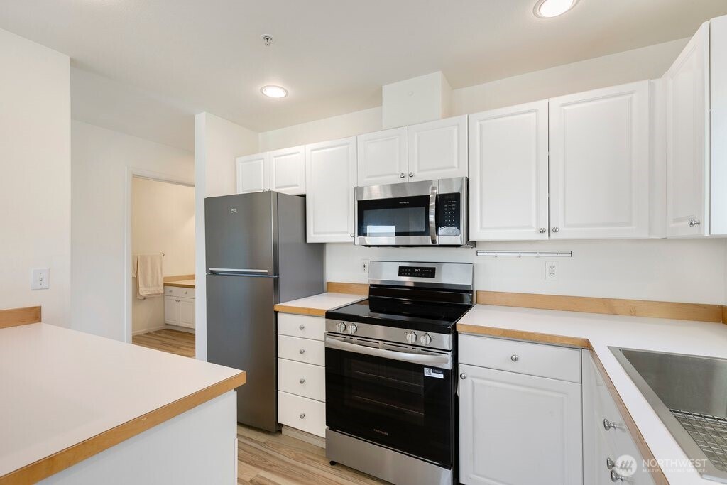 2101 North 55th Street, Unit 201 Seattle, WA 98103 - Photo 13 of 24 a kitchen with white cabinets and stainless steel appliances