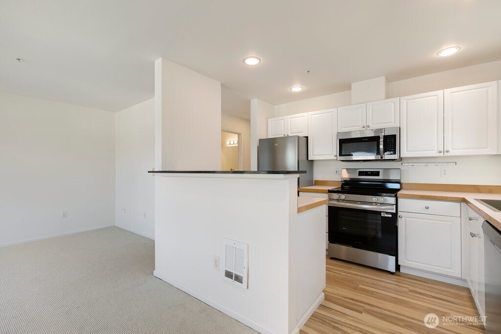 2101 North 55th Street, Unit 201 Seattle, WA 98103 - Photo 9 of 24 a kitchen with granite countertop white cabinets and stainless steel appliances