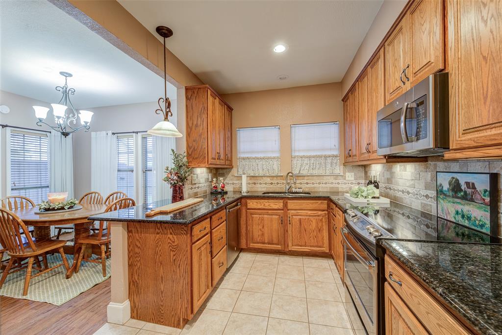 3602 Soft Wind Court Grapevine, TX 76051 - Photo 12 of 31 Kitchen with stainless steel appliances, brown cabinetry, and decorative backsplash
