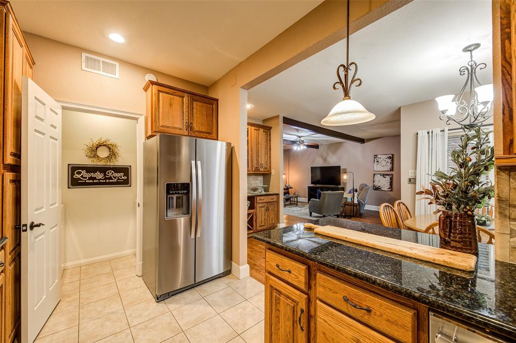 3602 Soft Wind Court Grapevine, TX 76051 - Photo 31 of 31 Kitchen featuring stainless steel refrigerator with ice dispenser, brown cabinetry, ceiling fan, open floor plan, and light tile patterned floors