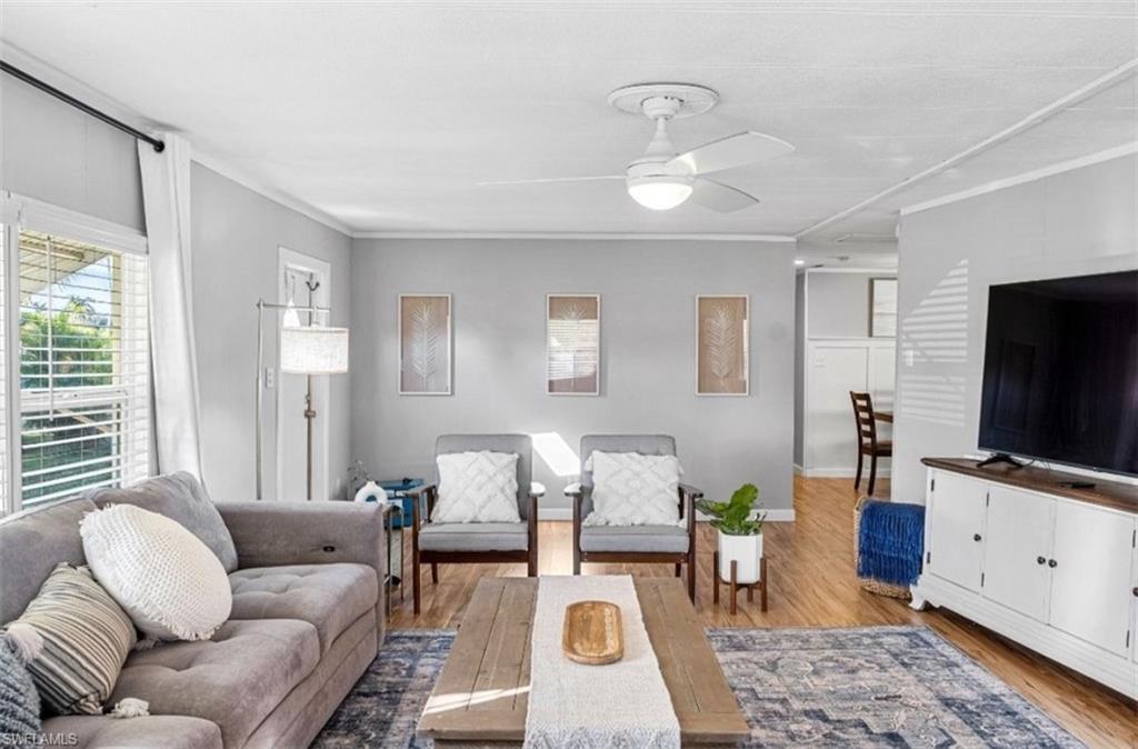Living room with wood finished floors, crown molding, and a ceiling fan