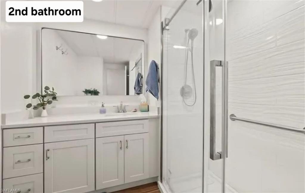 407 Cape Florida Way Naples, FL 34104 - Photo 15 of 27 Full bath featuring a stall shower, vanity, and dark wood-style floors