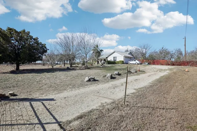 a view of a dry yard with wooden fence