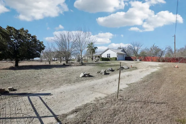 a view of a dry yard with wooden fence