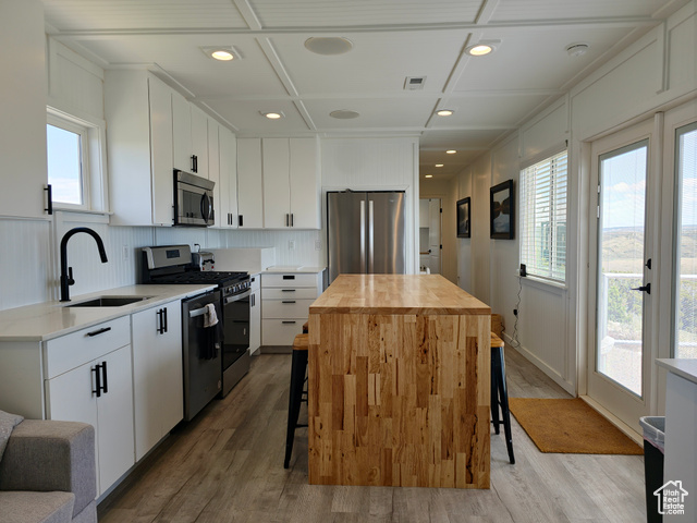 900 Altamont Road Evanston, WY 82930 - Photo 11 of 27 Kitchen featuring stainless steel appliances, butcher block counters, coffered ceiling, light wood finished floors, and a kitchen breakfast bar