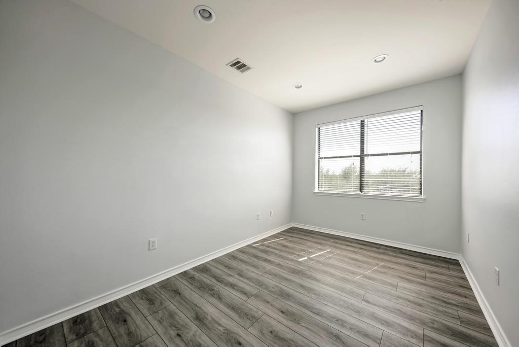 16201 Dodd Street Volente, TX 78641 - Photo 11 of 19 an empty room with wooden floor and windows