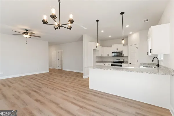 a view of a kitchen with kitchen island a sink stainless steel appliances and a chandelier