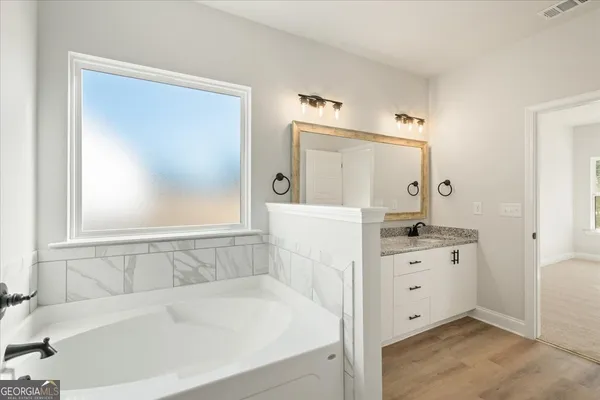 a bathroom with a tub sink and mirror