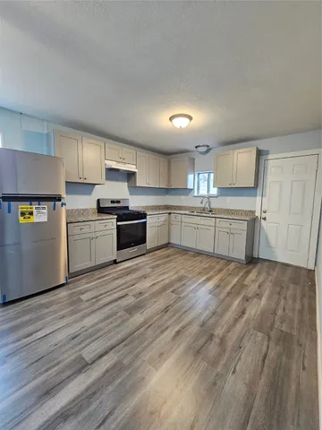 a kitchen with a cabinets wooden floor and stainless steel appliances
