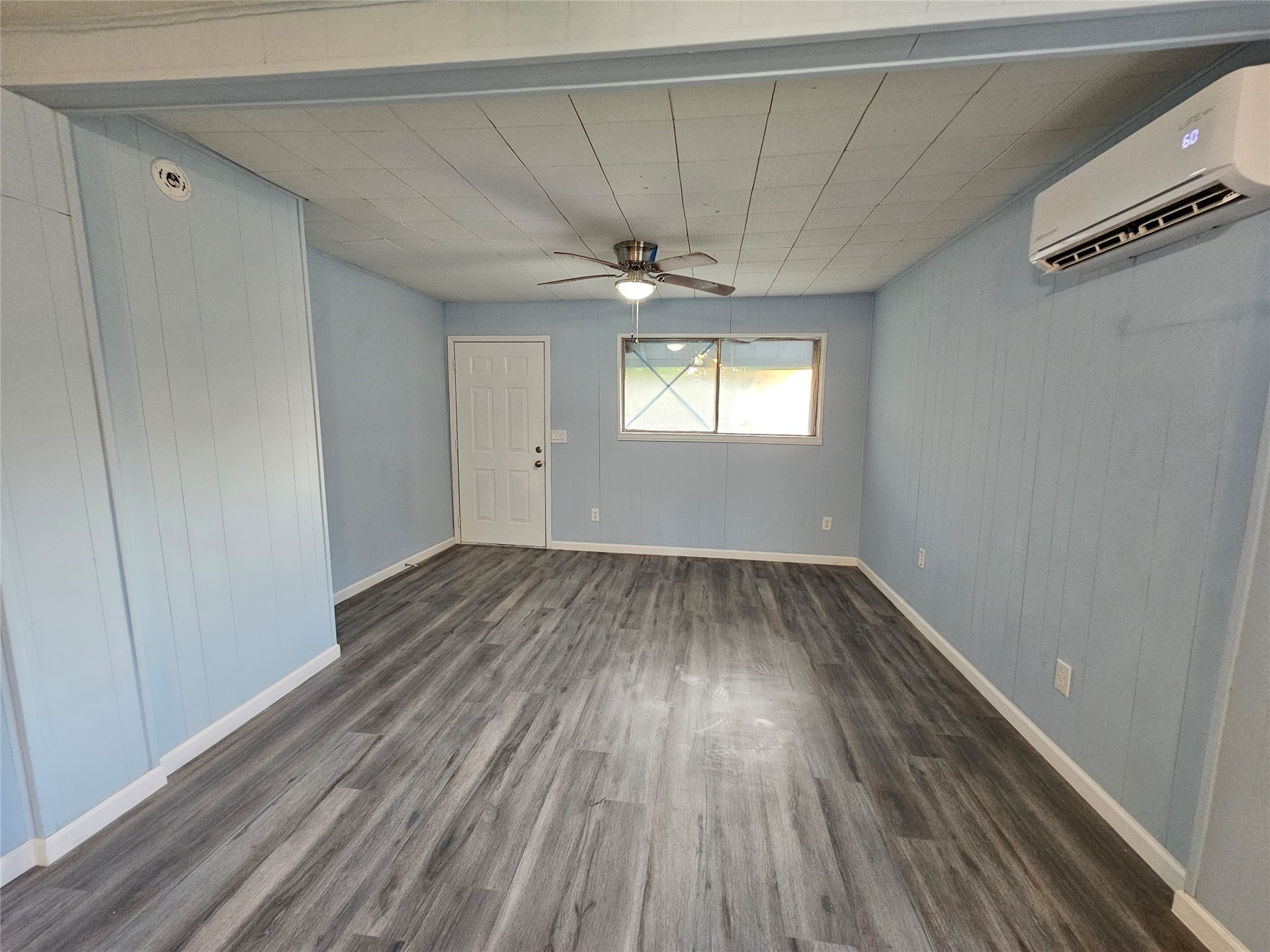 7808 Bauman Road Houston, TX 77022 - Photo 3 of 11 an empty room with wooden floor chandelier fan and windows