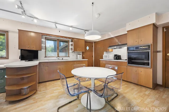 a kitchen with a dining table chairs and refrigerator
