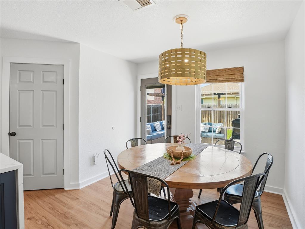 12724 Carpenter Lane Rhome, TX 76078 - Photo 11 of 37 Dining area featuring wood-finish flooring, a contemporary drum pendant light, and a window with a woven Roman shade