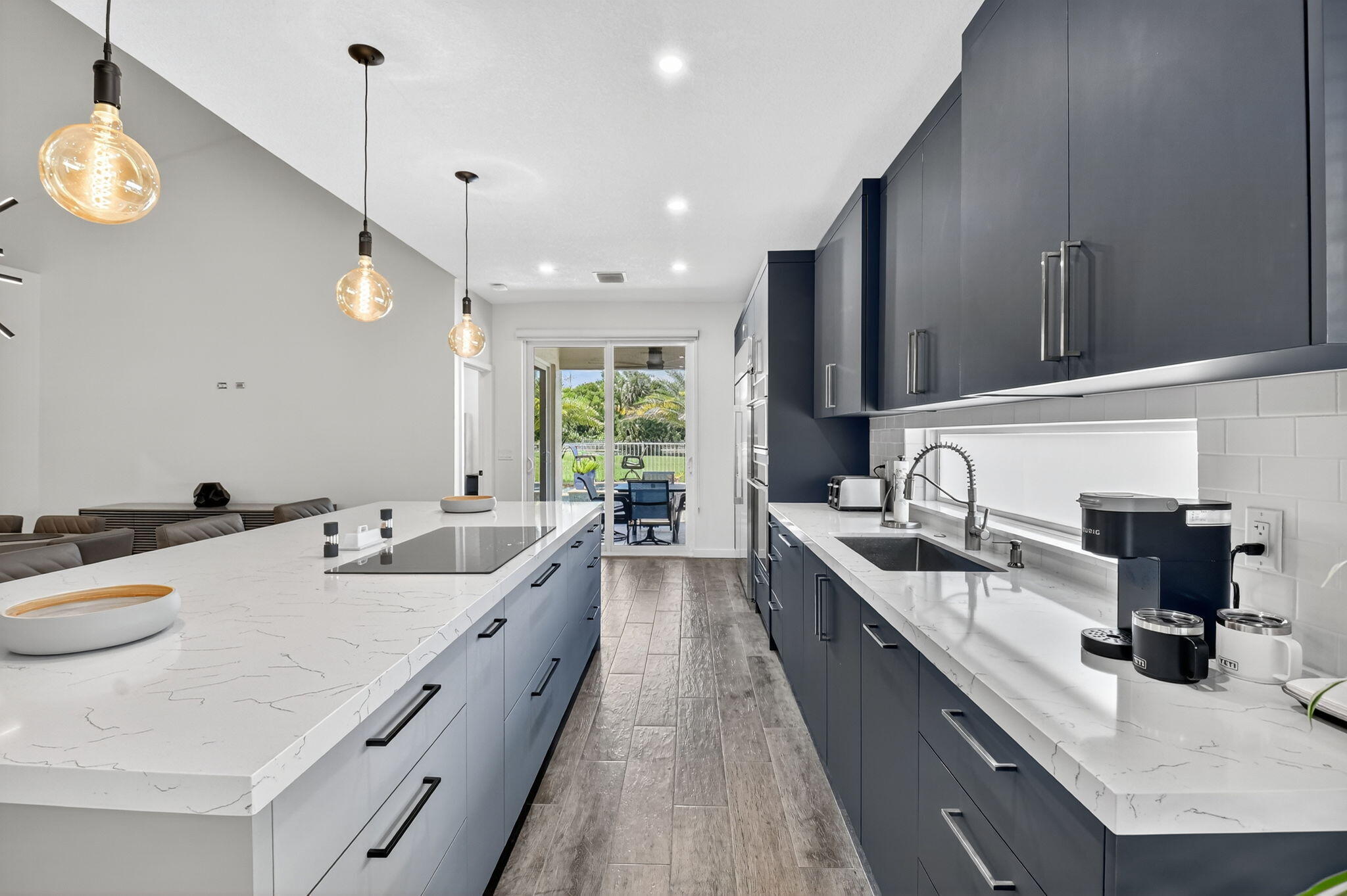 494 Enfield Court Delray Beach, FL 33444 - Photo 23 of 78 a large kitchen with kitchen island a large counter space a sink stainless steel appliances and cabinets