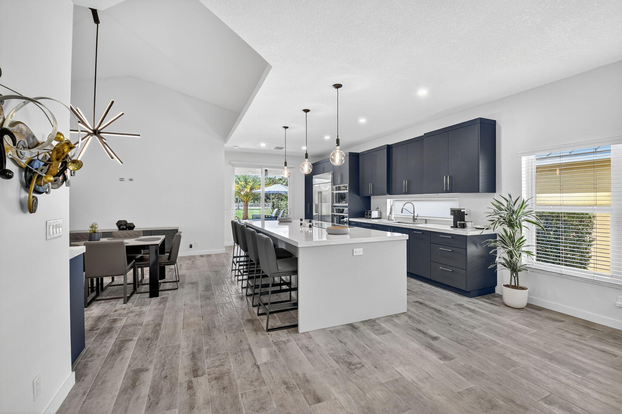 494 Enfield Court Delray Beach, FL 33444 - Photo 25 of 78 a kitchen with kitchen island stainless steel appliances a stove a sink a microwave a dining table and chairs