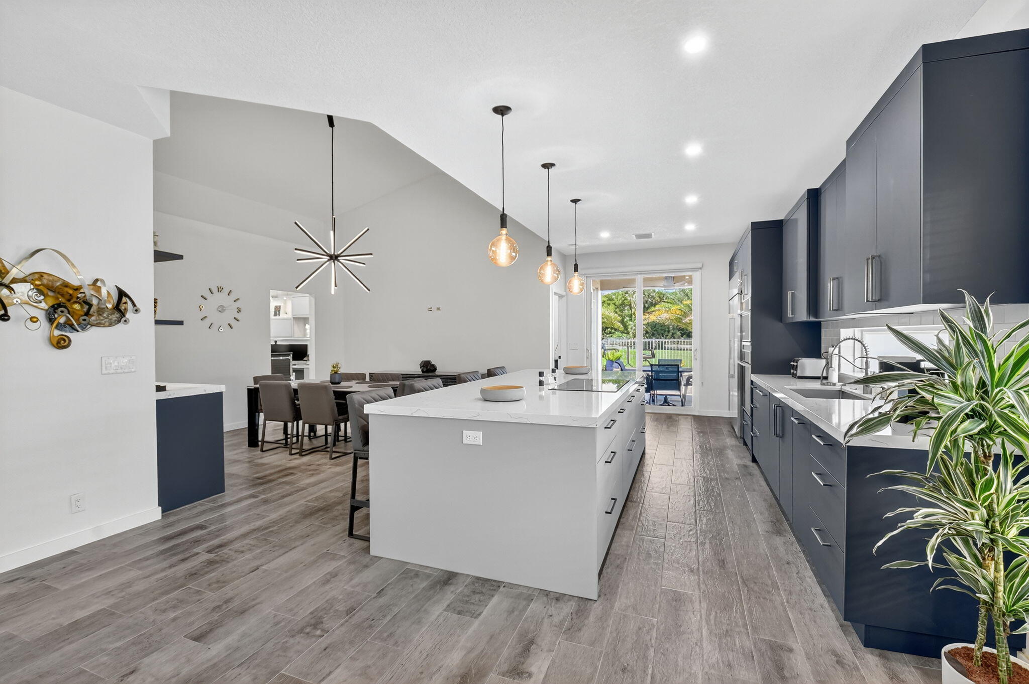 494 Enfield Court Delray Beach, FL 33444 - Photo 26 of 78 a large kitchen with a large center island wooden floor stainless steel appliances and living room view