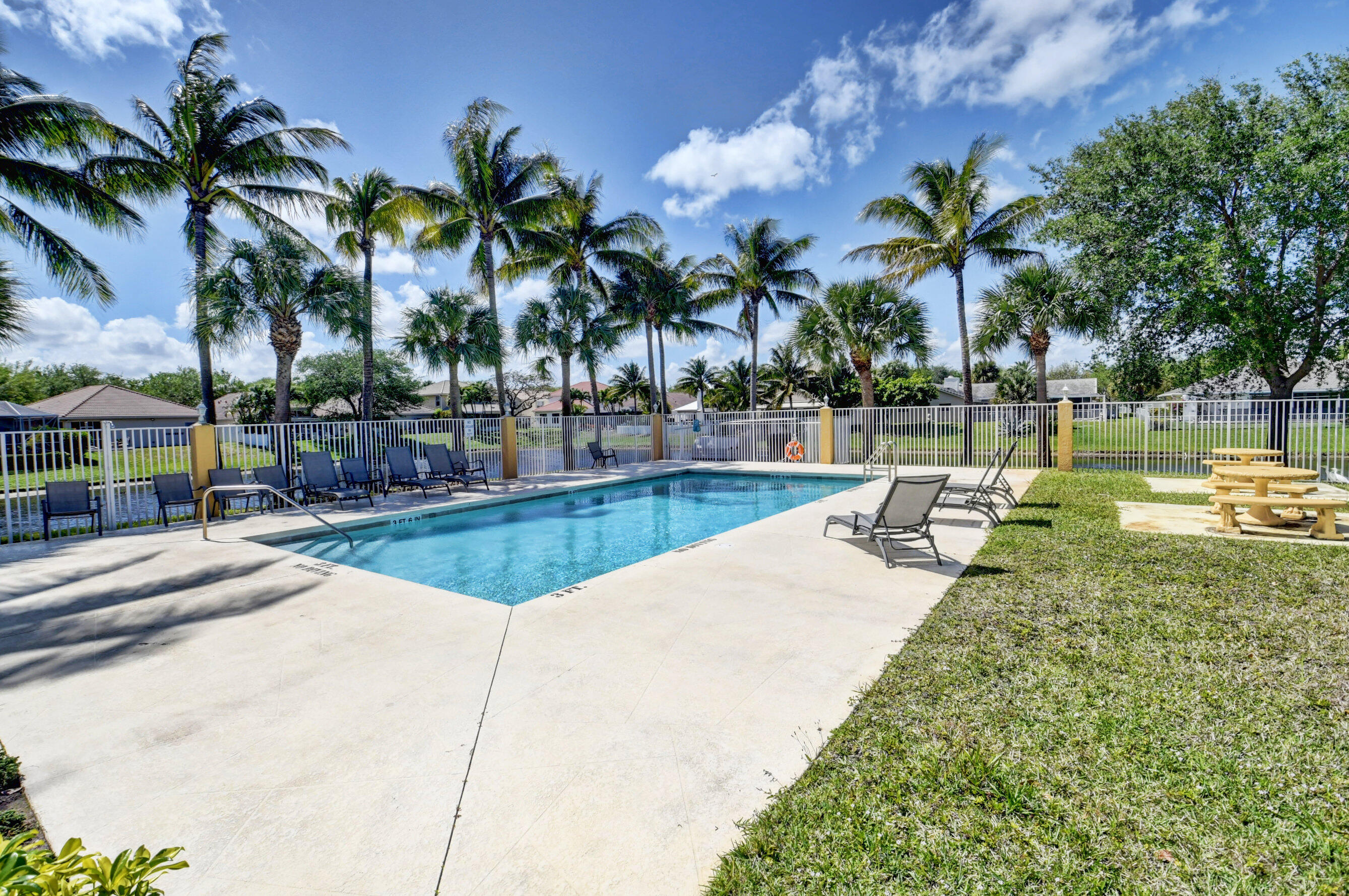 494 Enfield Court Delray Beach, FL 33444 - Photo 75 of 78 a view of a swimming pool with a lawn chairs and palm tree