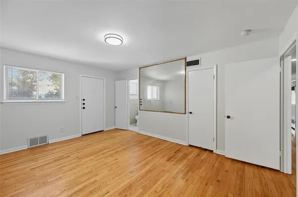 a view of empty room with wooden floor and window