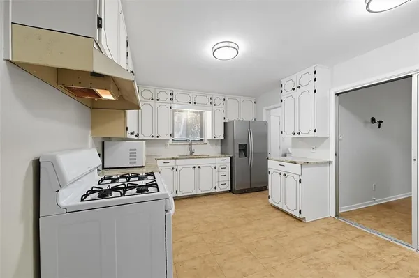 a kitchen with white cabinets and white appliances