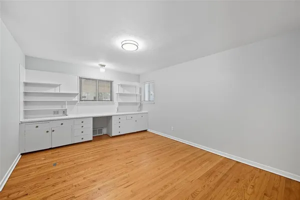 a big room with white cabinets and wooden floor