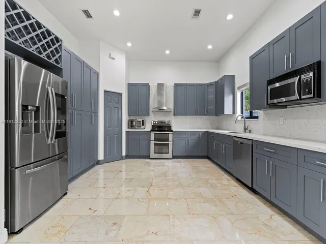 a kitchen with stainless steel appliances granite countertop a refrigerator and a sink