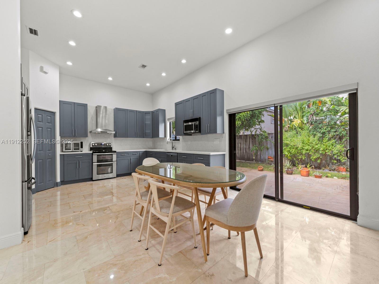 15871 Southwest 141st Street Miami, FL 33196 - Photo 12 of 41 a kitchen with stainless steel appliances granite countertop a stove a refrigerator a oven a sink with a dining table and chairs