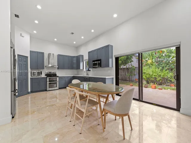 a kitchen with stainless steel appliances granite countertop a stove a refrigerator a oven a sink with a dining table and chairs