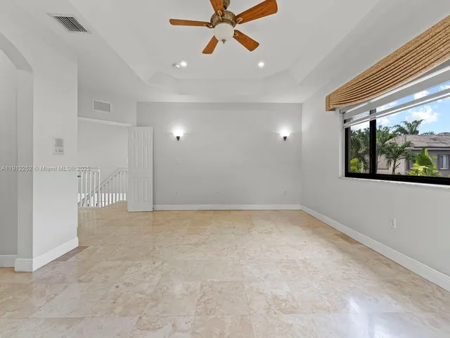 an empty room with ceiling fan and window