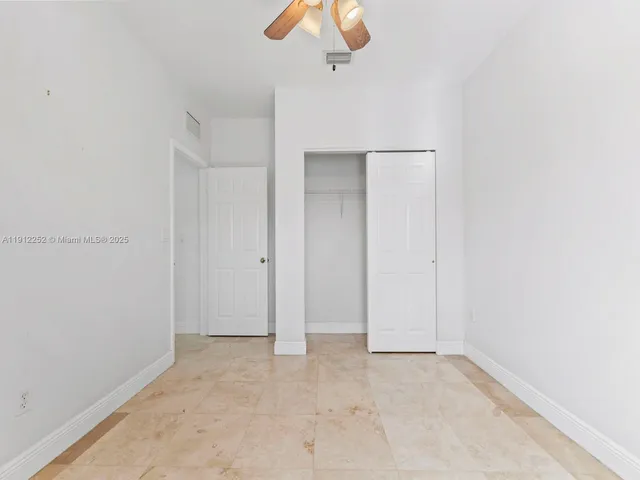 an empty room with a chandelier fan and windows