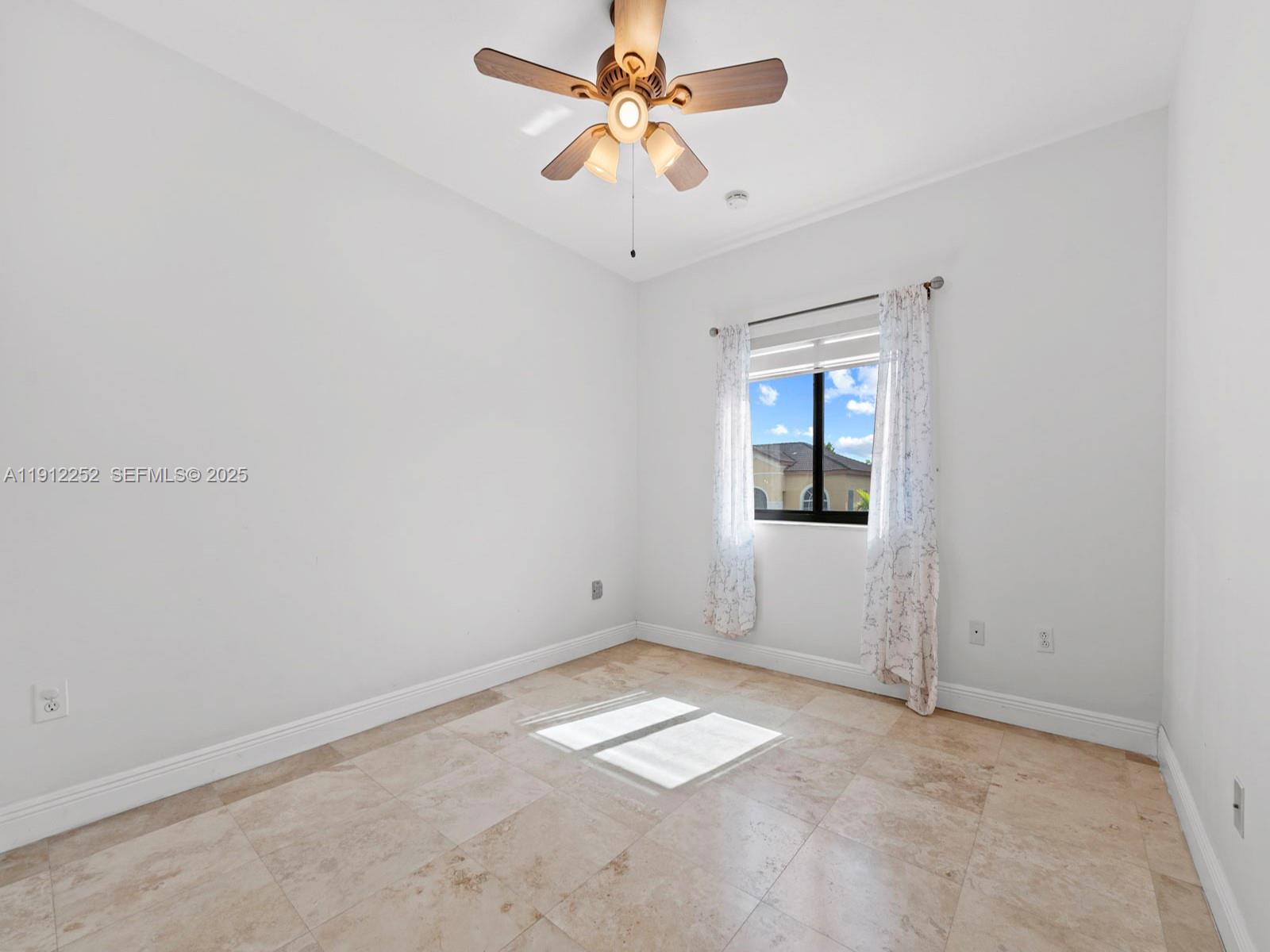 15871 Southwest 141st Street Miami, FL 33196 - Photo 27 of 41 an empty room with a chandelier fan and windows