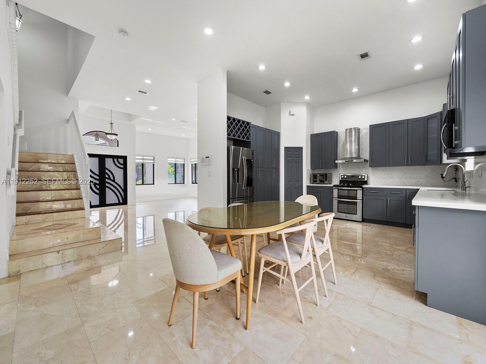 15871 Southwest 141st Street Miami, FL 33196 - Photo 8 of 41 a dining room with furniture a large window and stainless steel appliances