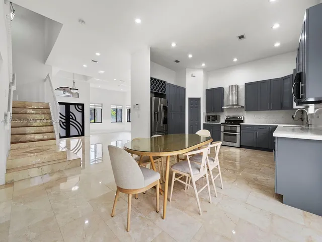a dining room with furniture a large window and stainless steel appliances