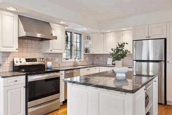 a kitchen with granite countertop a sink stainless steel appliances and white cabinets