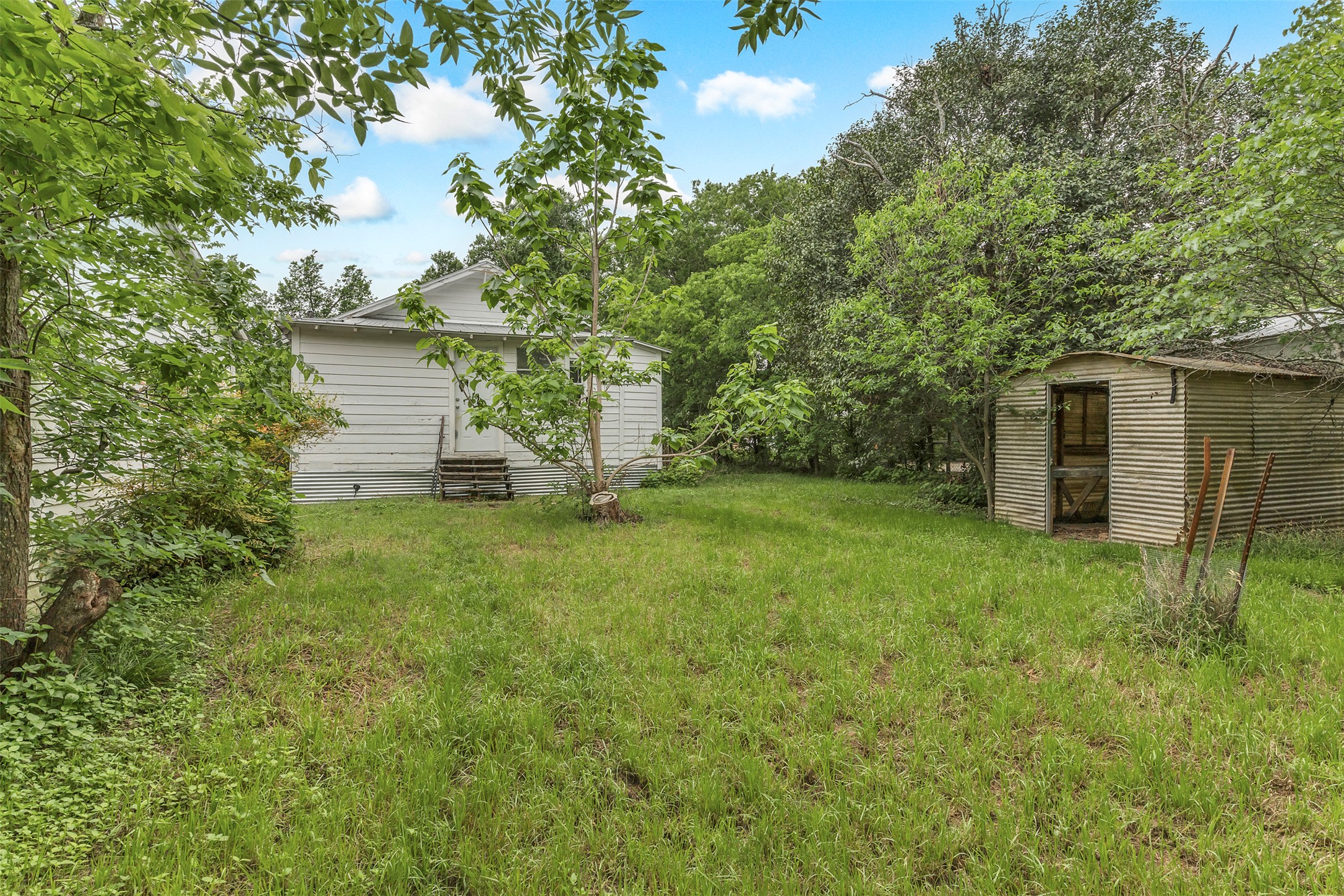 1002 Washburn Street Taylor, TX 76574 - Photo 28 of 29 The property features an extensive green lawn, mature trees, and a separate storage shed