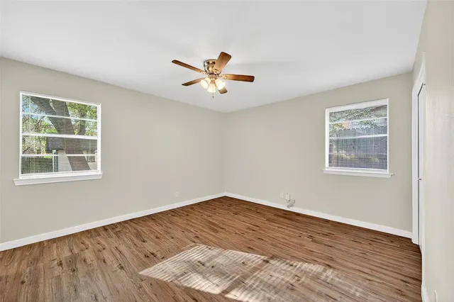 a view of an empty room with a window and wooden floor