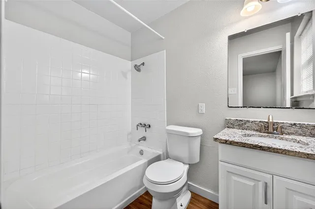 a bathroom with a granite countertop toilet a sink and a bathtub