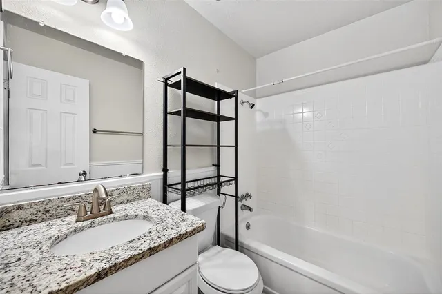 a bathroom with a granite countertop sink toilet and shower