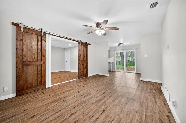 a view of empty room with wooden floor and fan