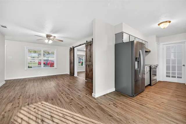 a view of an empty room with a window and a refrigerator