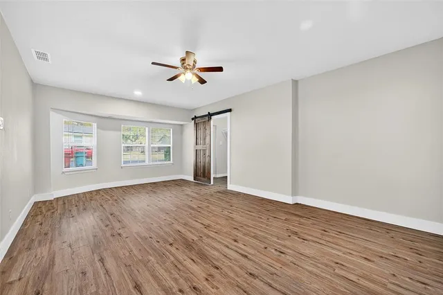 a view of empty room with wooden floor and ceiling fan